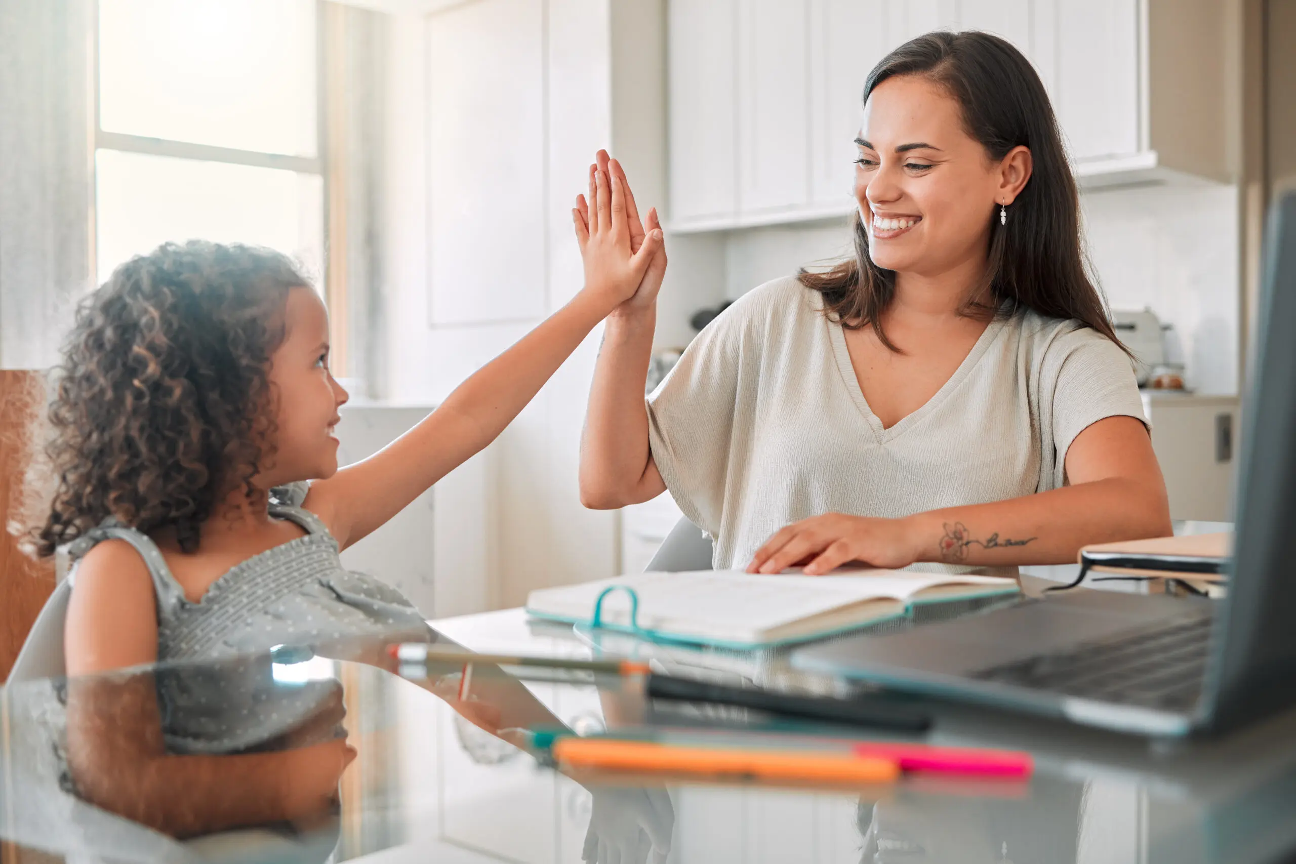 Girl and woman high-fiving in a bright kitchen