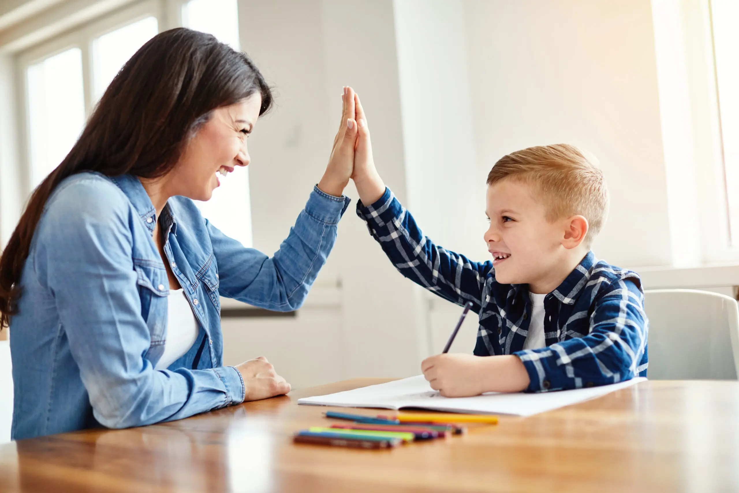 Mother and son giving a high five at a table