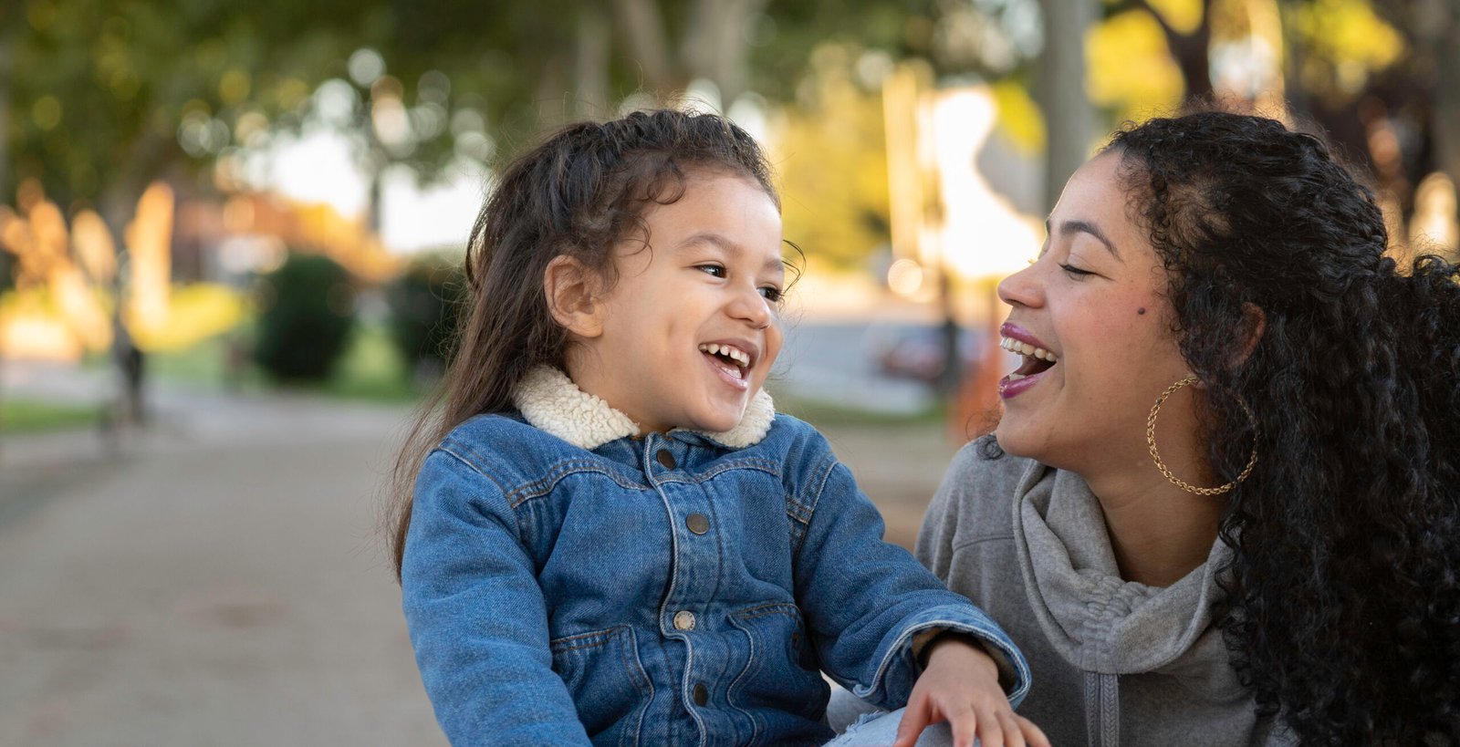Portrait of latin mother and daughter sharing a moment of joy and laughter together in a park, enjoying quality time A child and adult laughing together outdoors